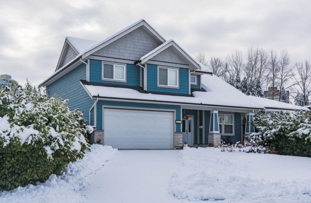 exterior of blue home covered in a layer of snow